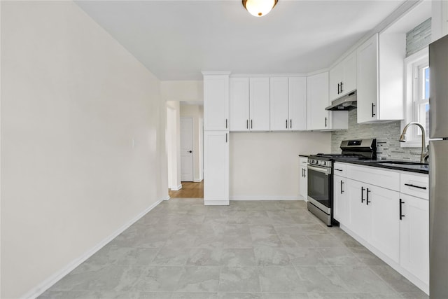 kitchen featuring white cabinetry, stainless steel gas range oven, backsplash, under cabinet range hood, and a sink