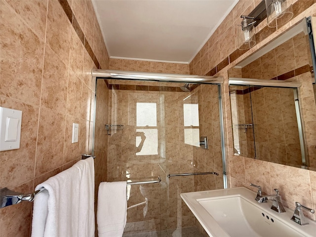 bathroom featuring a stall shower, a sink, and tile walls