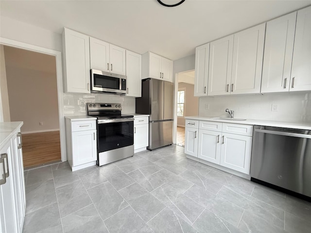 kitchen with white cabinetry, backsplash, light countertops, and appliances with stainless steel finishes