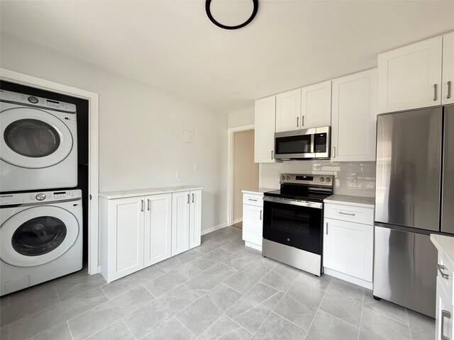 kitchen with decorative backsplash, light countertops, stacked washer / dryer, stainless steel appliances, and white cabinetry