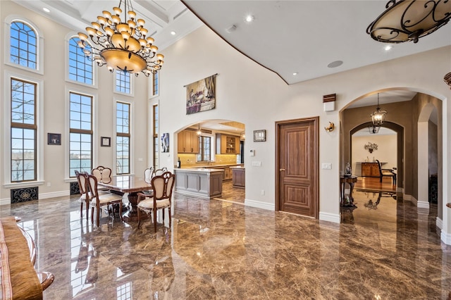 117 Malba Dr, Malba, NY 11357 - dining space featuring plenty of natural light, a chandelier, marble finish floor, arched walkways, and a towering ceiling