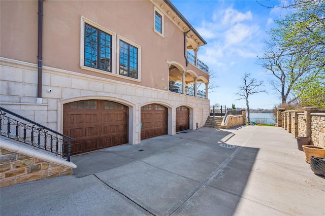 117 Malba Dr, Malba, NY 11357 - view of property exterior featuring a balcony, stucco siding, driveway, stone siding, and a garage