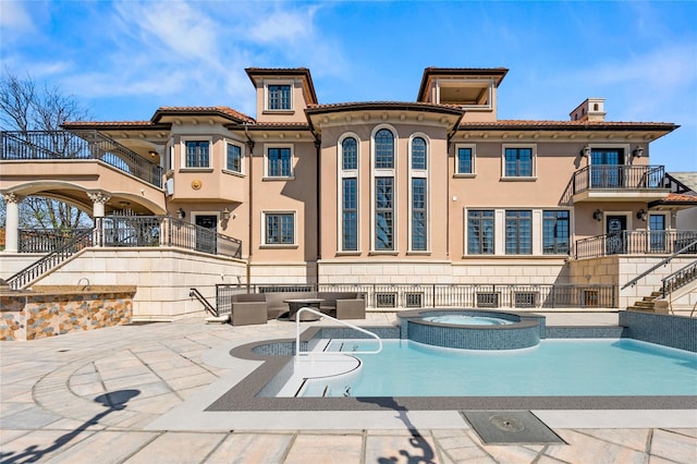 117 Malba Dr, Malba, NY 11357 - back of property with stucco siding, a pool with connected hot tub, stairs, and a balcony
