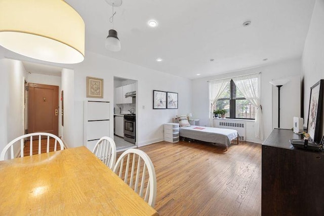 bedroom featuring radiator heating unit, baseboards, recessed lighting, and light wood-type flooring