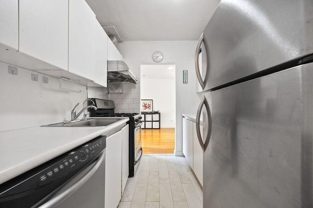 kitchen with decorative backsplash, appliances with stainless steel finishes, light countertops, light wood finished floors, and white cabinetry