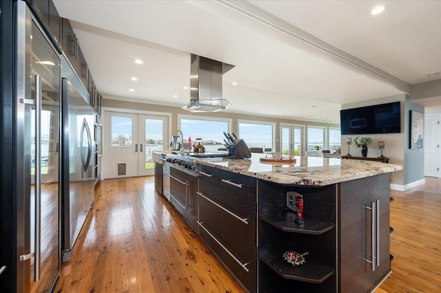 kitchen with light wood finished floors, extractor fan, appliances with stainless steel finishes, and french doors
