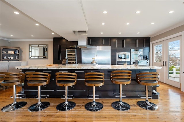 kitchen featuring light wood-style flooring, crown molding, built in appliances, and a large island
