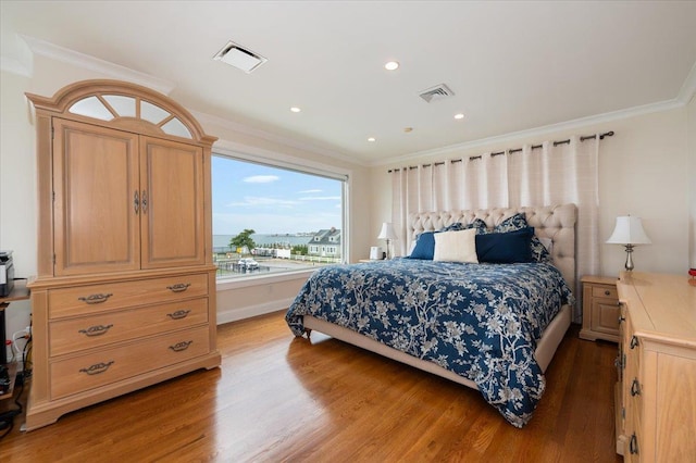 bedroom featuring crown molding, wood finished floors, and visible vents