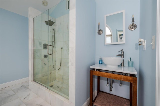 full bath with marble finish floor, baseboards, a sink, and a stall shower