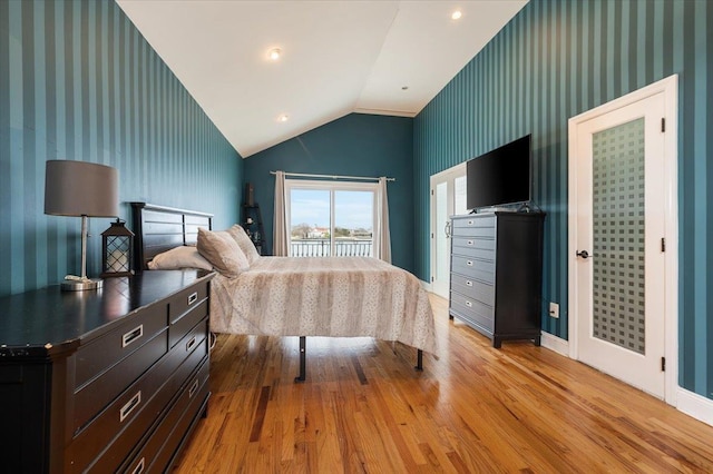 bedroom with wallpapered walls, vaulted ceiling, wood finished floors, and access to outside