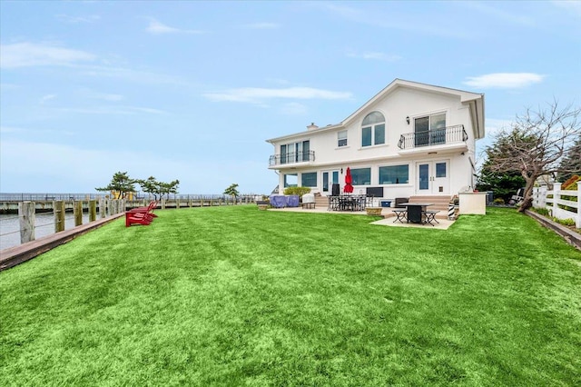 back of property featuring a fenced backyard, a balcony, a patio area, french doors, and a lawn