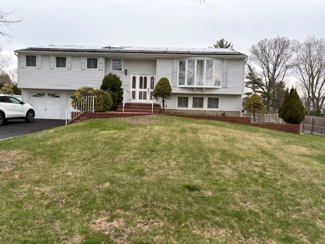 19 Yeoman Dr, East Northport, NY 11731 - raised ranch featuring roof mounted solar panels, driveway, a front yard, and a garage