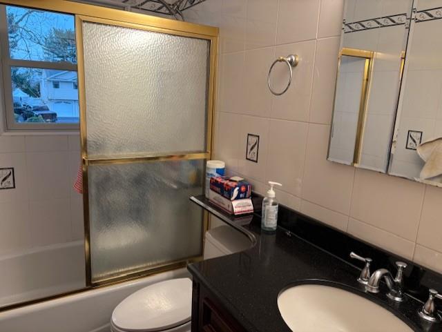 19 Yeoman Dr, East Northport, NY 11731 - full bathroom featuring vanity, shower / bath combination with glass door, tile walls, toilet, and backsplash