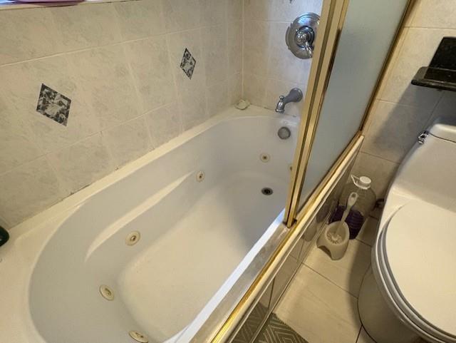 19 Yeoman Dr, East Northport, NY 11731 - full bathroom featuring tile patterned floors, a combined bath / shower with jetted tub, toilet, and tile walls