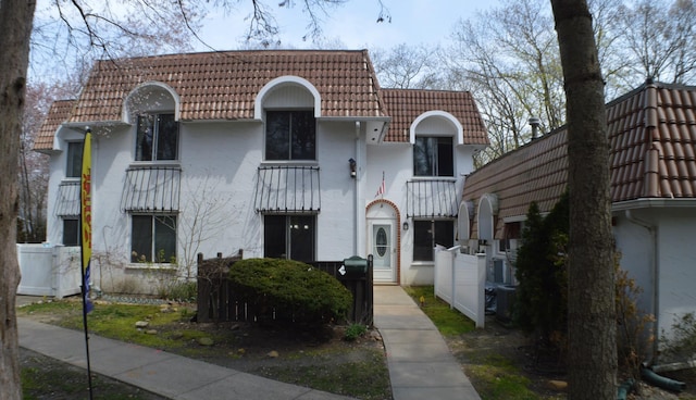 view of front of property featuring stucco siding, a tile roof, and a balcony