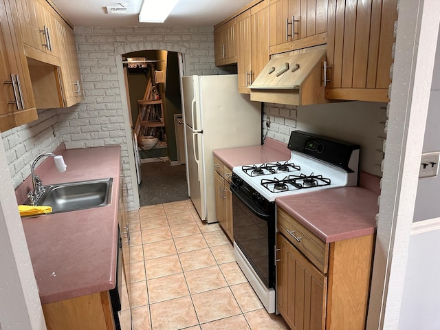 kitchen featuring a sink, light tile patterned flooring, freestanding refrigerator, gas stove, and under cabinet range hood