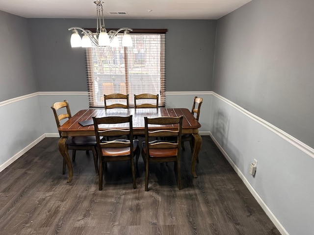 dining space with dark wood-type flooring, visible vents, baseboards, and an inviting chandelier