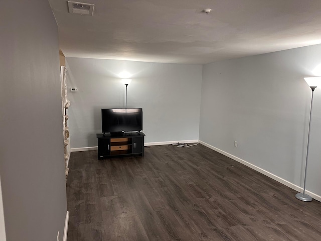unfurnished living room featuring baseboards, visible vents, and dark wood finished floors