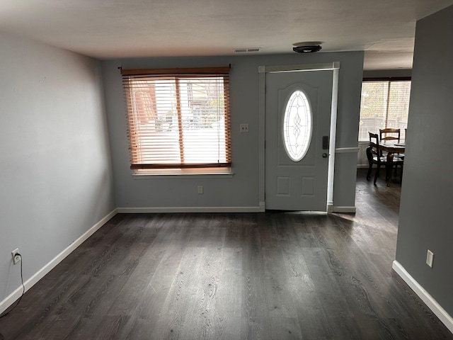 foyer with baseboards, visible vents, and dark wood-style floors
