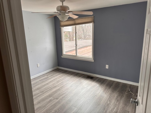 spare room with baseboards, a ceiling fan, wood finished floors, and visible vents