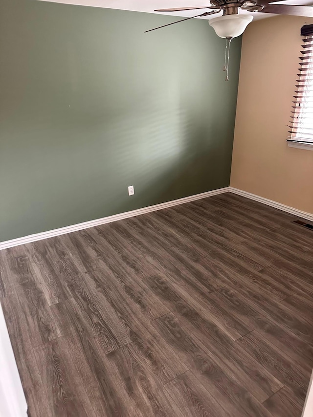 spare room featuring ceiling fan, baseboards, dark wood-style floors, and visible vents