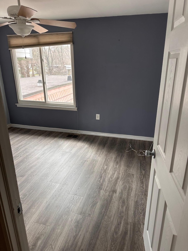 spare room with baseboards, wood finished floors, visible vents, and ceiling fan