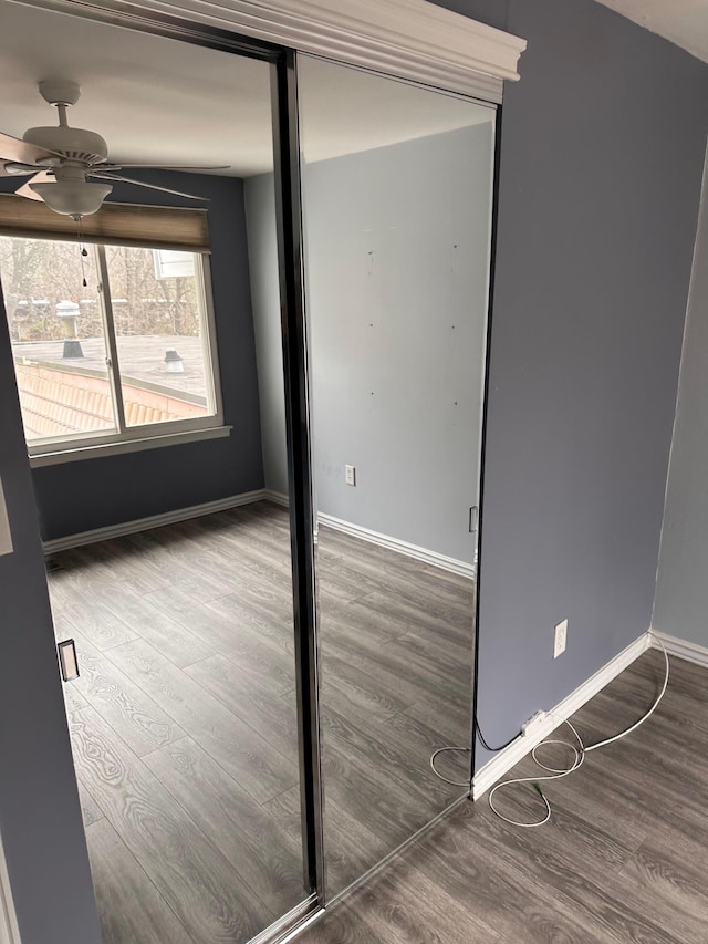 empty room featuring wood finished floors, a ceiling fan, and baseboards
