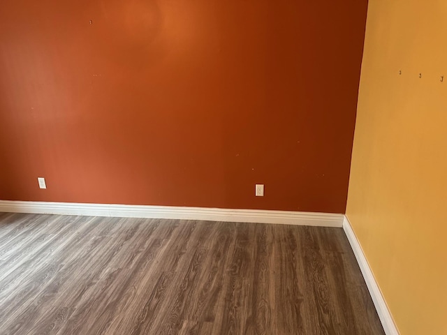 spare room with baseboards and wood finished floors