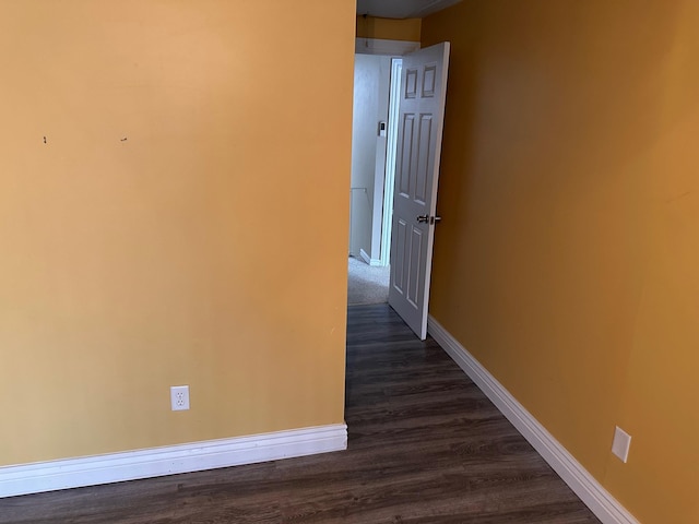 corridor featuring baseboards and dark wood-style flooring