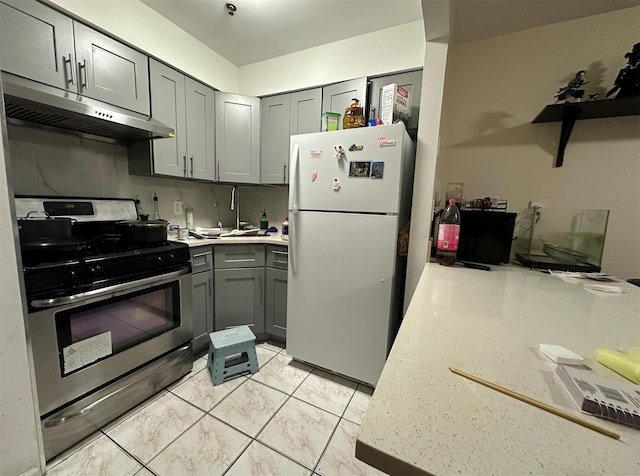 108-14 35th Ave, Corona, NY 11368 - kitchen with stainless steel range with gas stovetop, under cabinet range hood, a sink, gray cabinets, and freestanding refrigerator