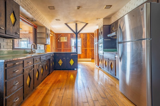 kitchen featuring light wood-style floors, a peninsula, stainless steel counters, a sink, and stainless steel appliances