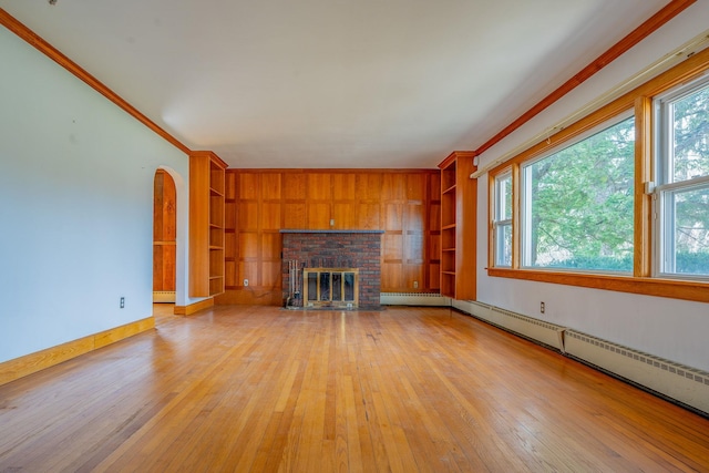 unfurnished living room featuring light wood-type flooring, built in features, ornamental molding, and a baseboard radiator