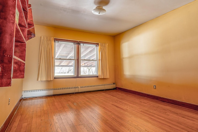 empty room with wood-type flooring, a baseboard radiator, and baseboards
