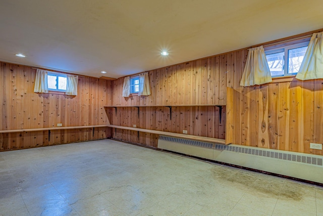 basement featuring tile patterned floors, a baseboard heating unit, wooden walls, and recessed lighting