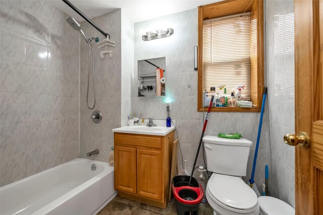 bathroom featuring toilet, vanity, shower / tub combination, and tile walls
