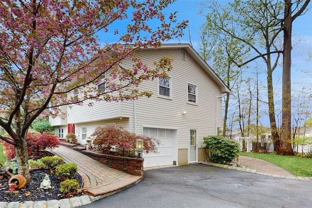 view of side of home featuring an attached garage and aphalt driveway
