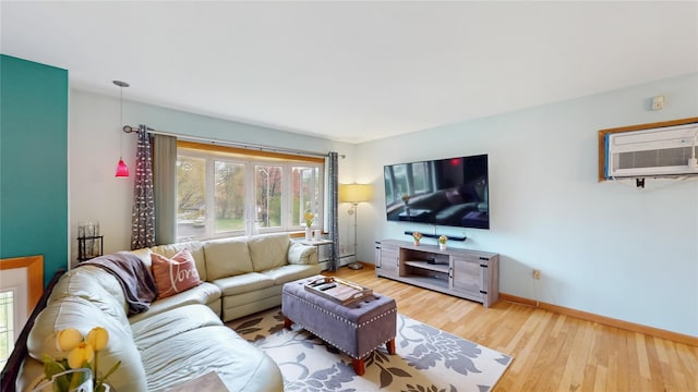 living area with baseboards, light wood-style flooring, and a wall mounted air conditioner