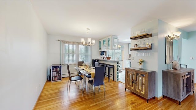 dining room featuring an inviting chandelier, light wood finished floors, and a baseboard heating unit