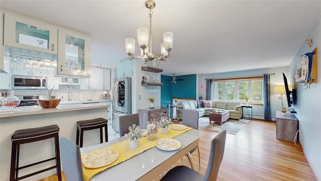 dining space featuring light wood-type flooring, a baseboard radiator, and a notable chandelier