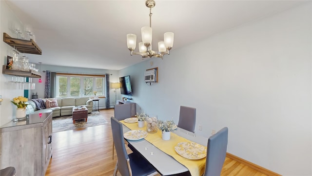 dining space featuring light wood-style floors, baseboards, and a notable chandelier