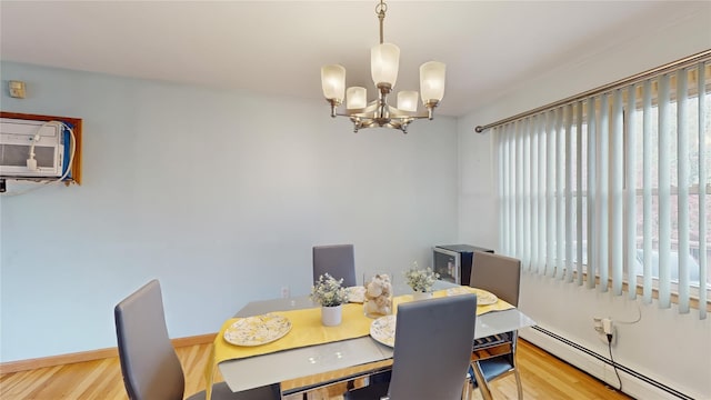 dining space with a chandelier, baseboards, a baseboard heating unit, and wood finished floors