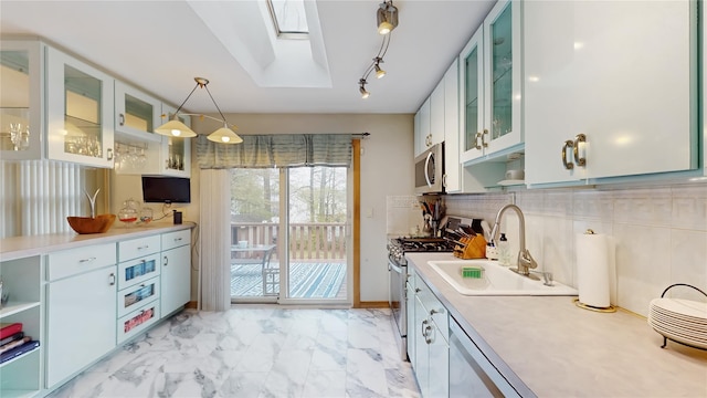 kitchen with appliances with stainless steel finishes, a sink, light countertops, marble finish floor, and a skylight