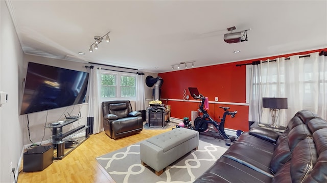 living room with rail lighting, wood finished floors, and a wood stove