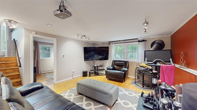 living area featuring stairs, a baseboard heating unit, track lighting, and wood finished floors