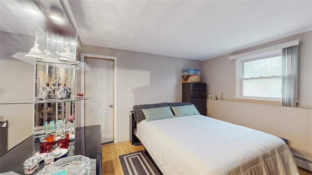 bedroom featuring a baseboard heating unit and light wood-type flooring