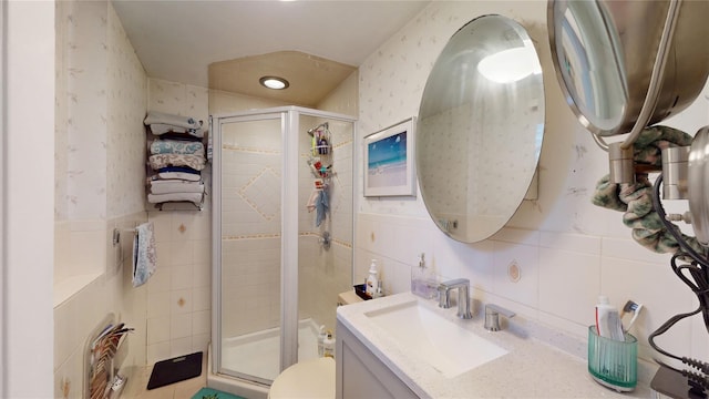 full bath with wallpapered walls, vanity, a shower stall, and tile walls