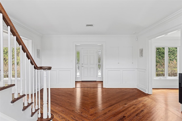 foyer entrance with visible vents, ornamental molding, wood finished floors, and stairs