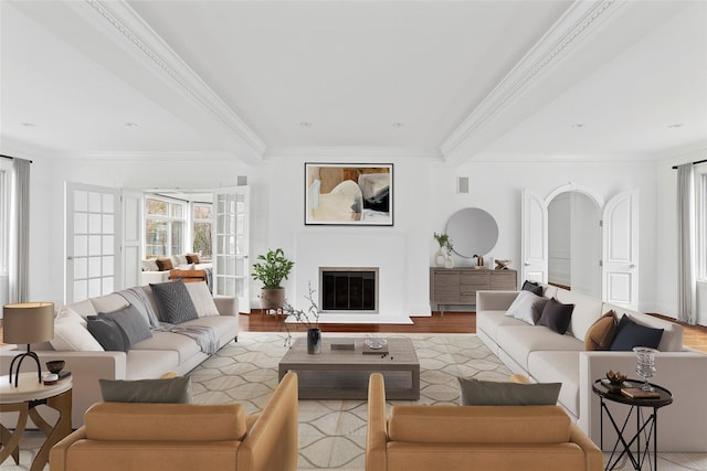 living area featuring a glass covered fireplace, visible vents, crown molding, and wood finished floors