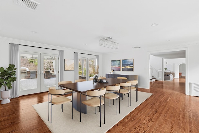 dining room with french doors, wood finished floors, visible vents, and stairs