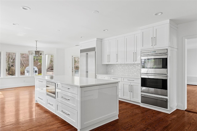 kitchen with a warming drawer, built in appliances, and dark wood finished floors